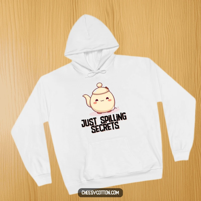 Funny hoodie featuring a shy teapot character peeking from behind a steaming teabag, offering cozy comfort and a touch of whimsical humor.